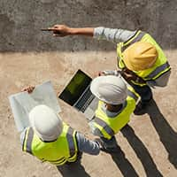 Three workers in hardhats discussing plans